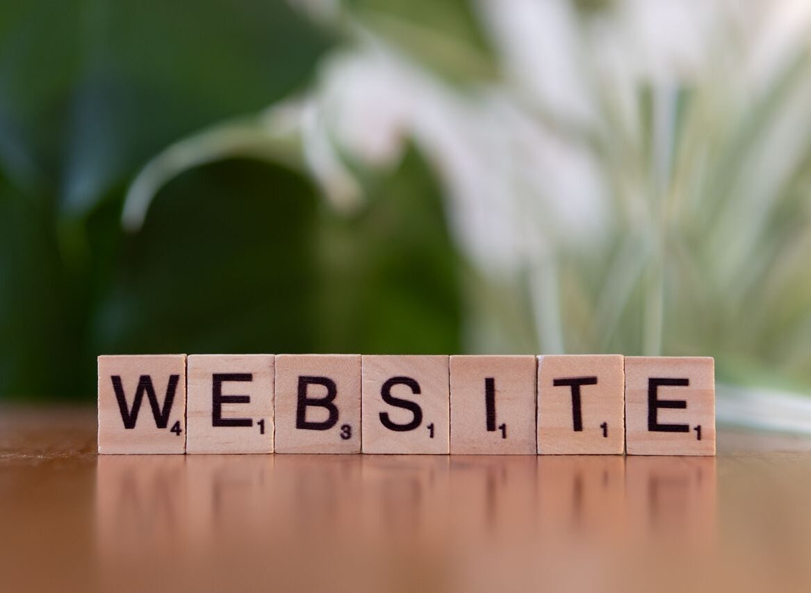 Scrabble tiles on a wooden surface forming the word 'Website', symbolizing digital communication.